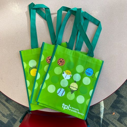 Three bright green tote bags on a table, laid flat and overlapping. The ...