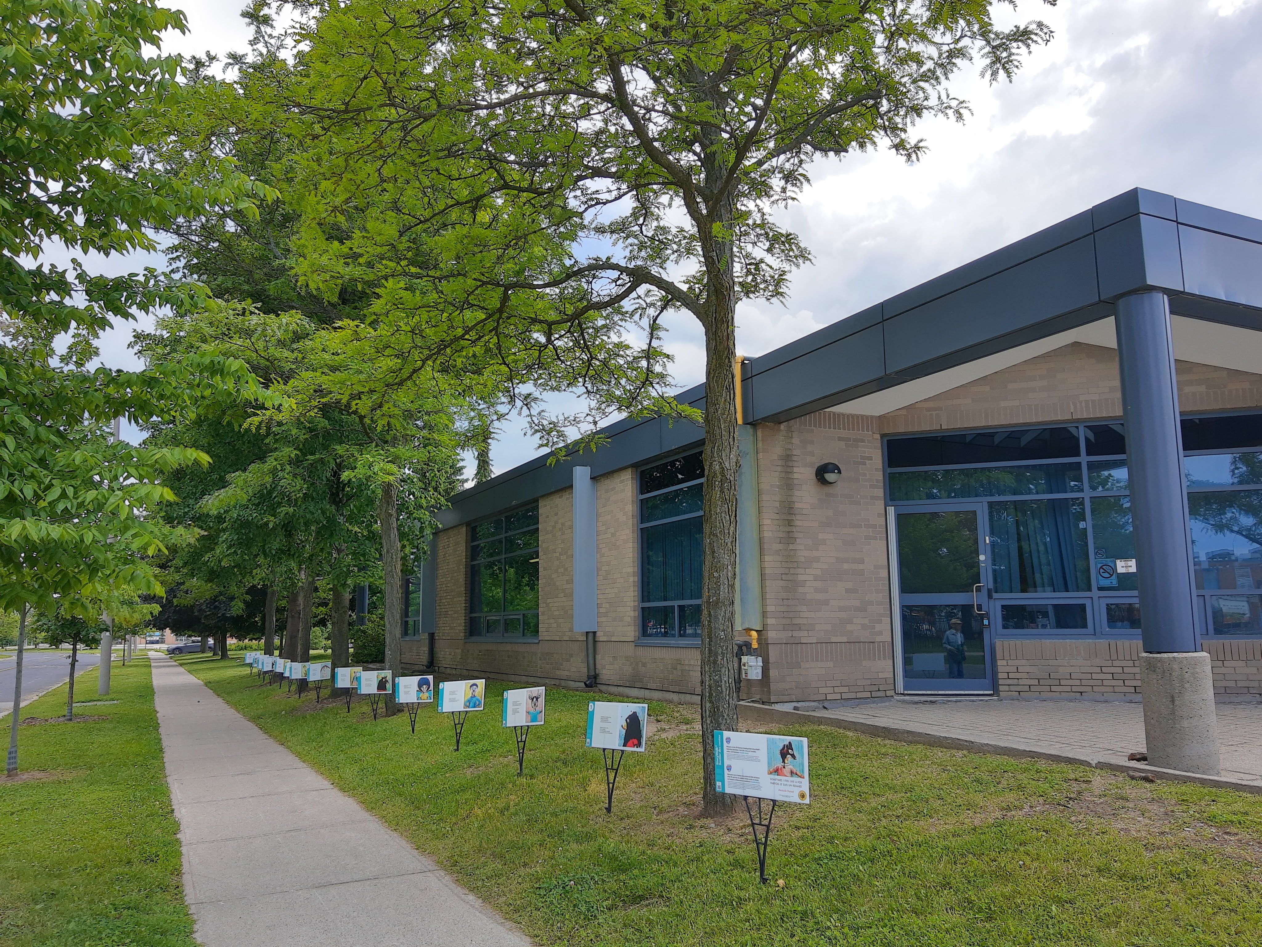StoryWalk panels standing along the tree-lined sidewalk outside Goldhawk Park Branch.
